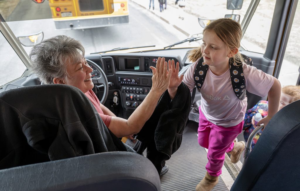 a bus driver high fiving a student.