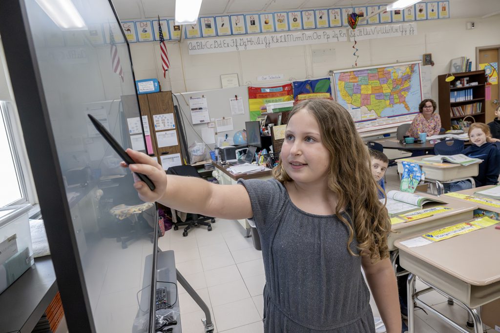 a student uses a stylus in front of a white board.