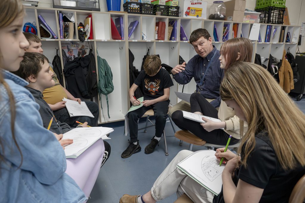 a teacher engaging a circle of students in discussion.