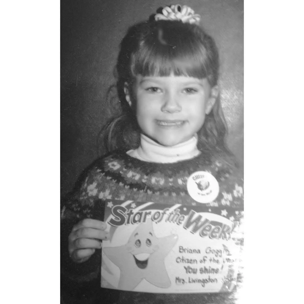 young student in a black and white image, receiving a star of the week award, alumni biranna goggin