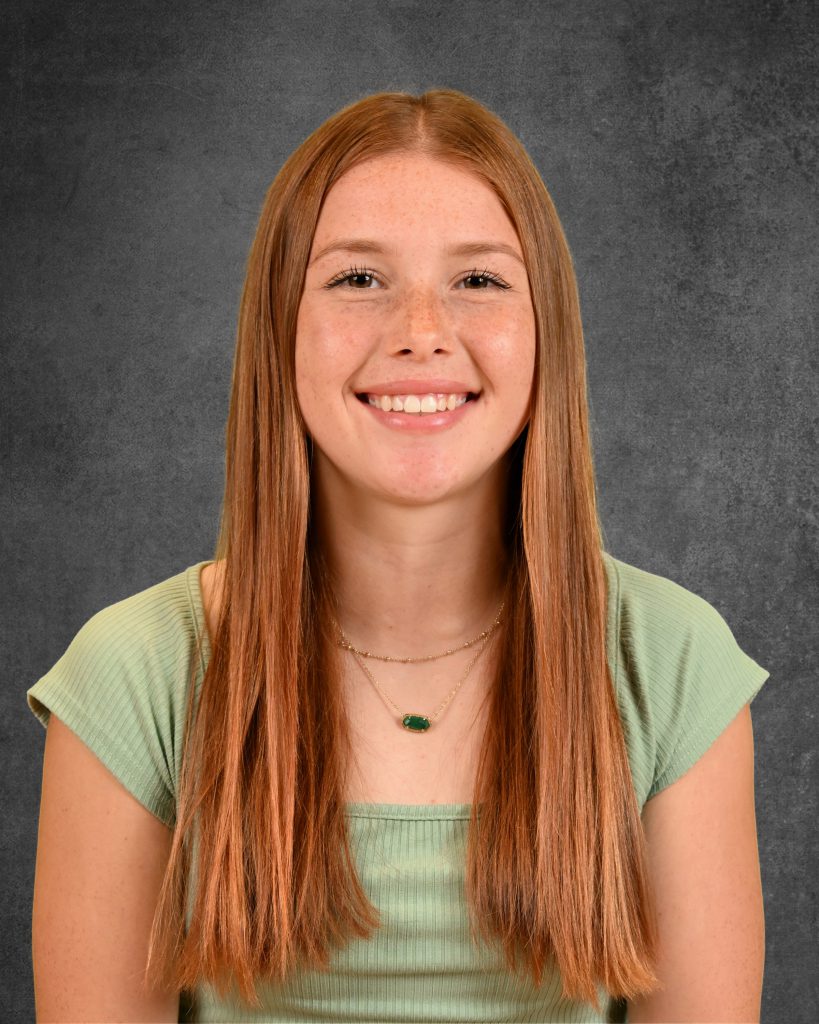 student, Amelia Guarascio, posing for student picture day, smiling, wearing green top and green emerald type necklace