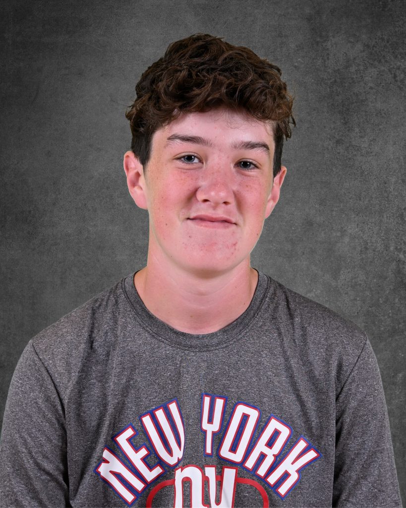 student, Noah Lamphere, posing for student picture day, smiling, wearing grey shirt saying new york