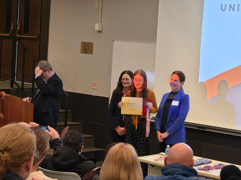 student recieiving a certificate from utica university science fair
