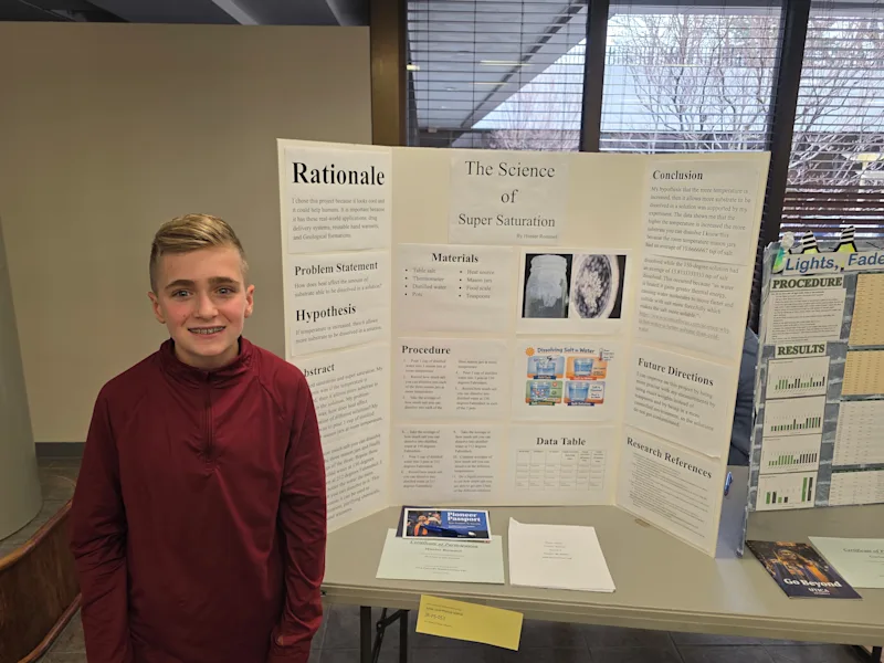 young student standing with their science project, 'the science of super saturation', at the utica university science fair