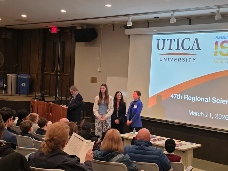 student recieiving a certificate and award from utica university science fair