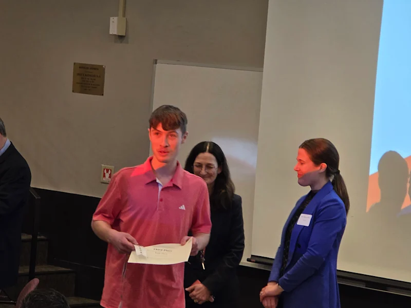 student recieiving a certificate and ribbon from utica university science fair