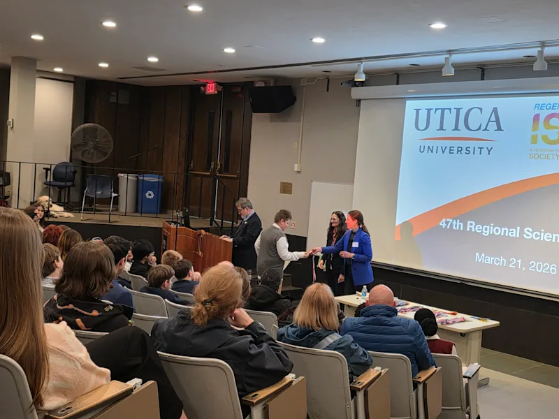 young student receiving a ribbon at the utica university science fair