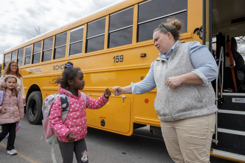 student giving a fist bump to bus driver