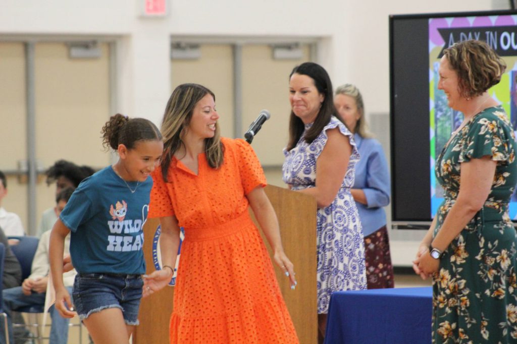 teachers smiling as student walks up to them