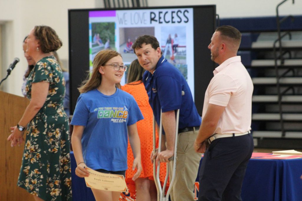 student smiling with award in hand and walking