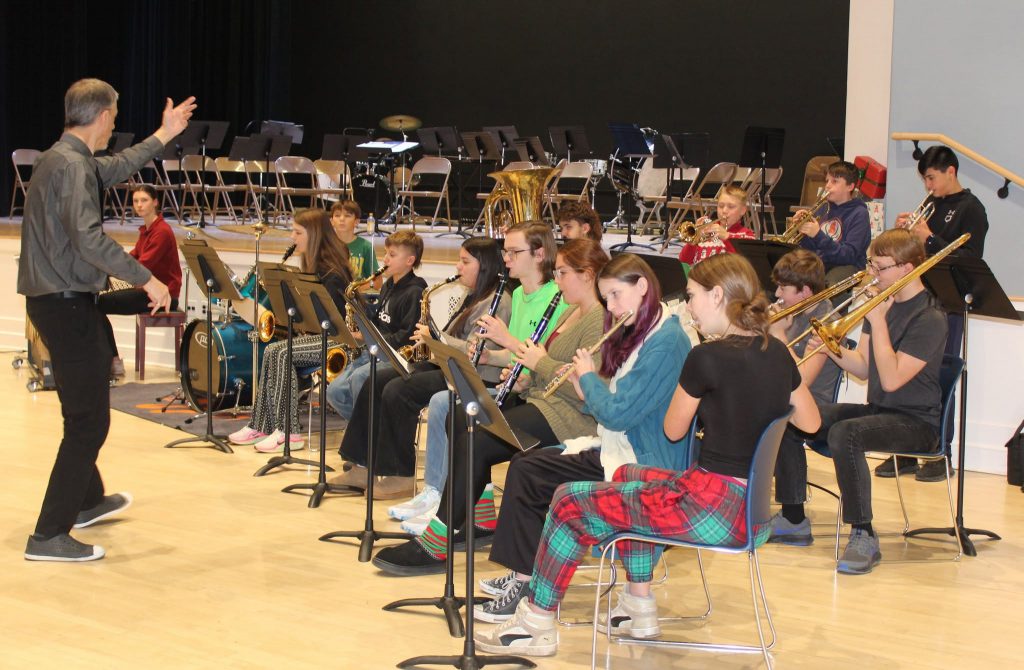 Band of students playing instruments while sat.